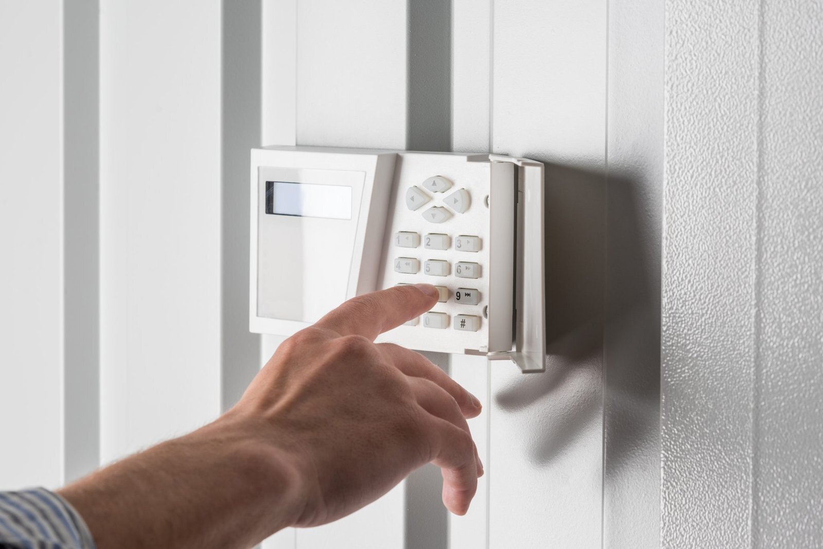 Hand entering a code on a home security alarm keypad