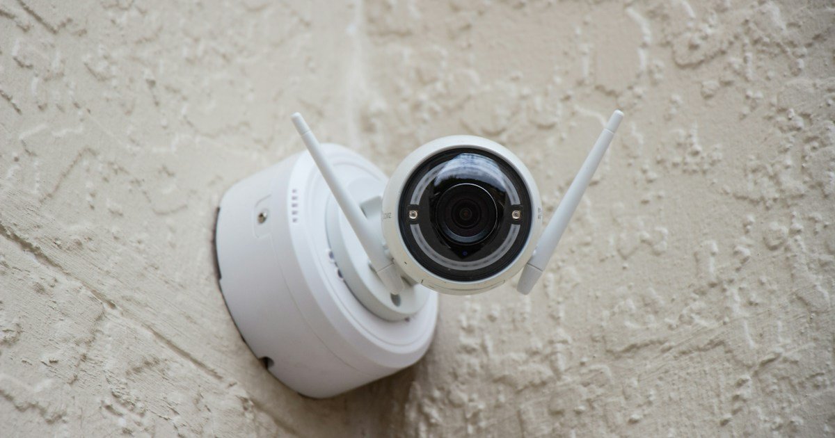 White outdoor security camera mounted on a stucco wall